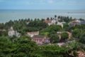 Colonial rooftops and church towers in Olinda, with the Atlantic beyond.